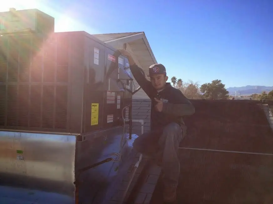 HVAC technician performing Air Duct Repair on a rooftop unit in Birmingham